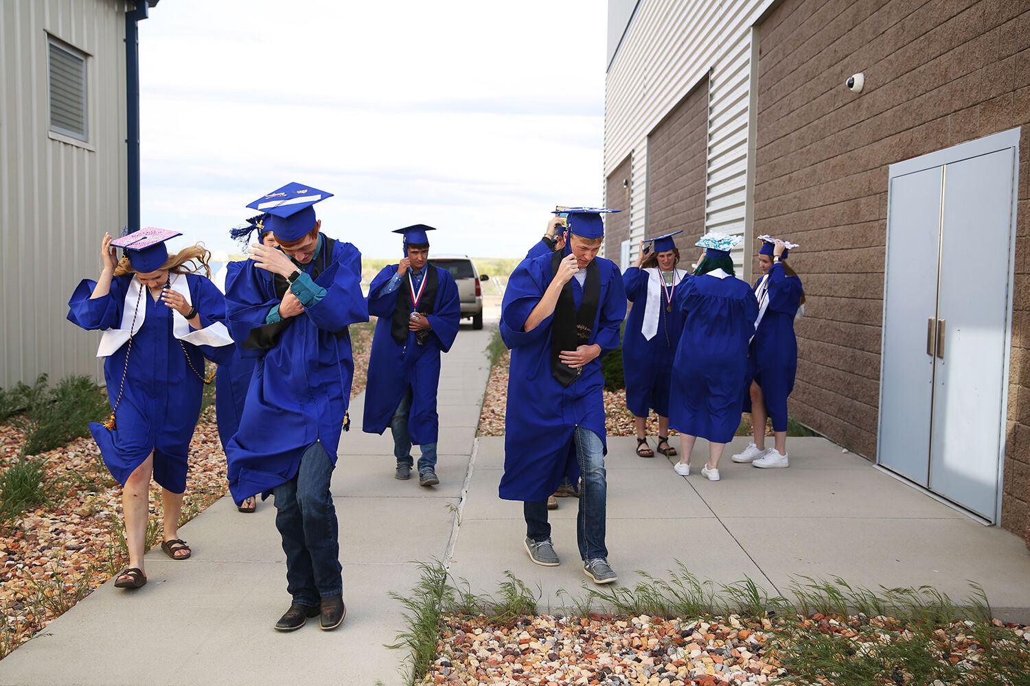 graduates walk back into the school to get out of the wind